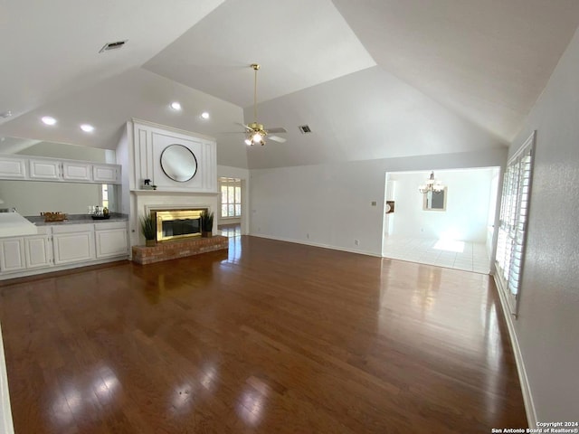 unfurnished living room with ceiling fan, dark hardwood / wood-style flooring, lofted ceiling, and a brick fireplace