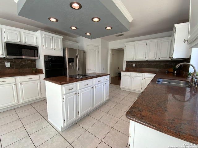 kitchen featuring tasteful backsplash, sink, black appliances, white cabinets, and a center island