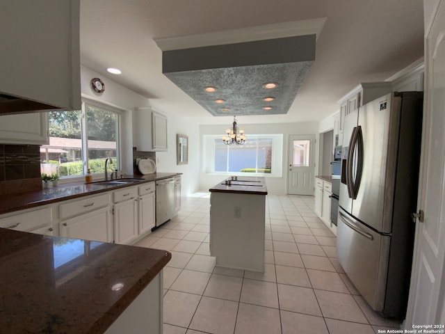 kitchen featuring stainless steel appliances, a tray ceiling, sink, white cabinets, and a center island