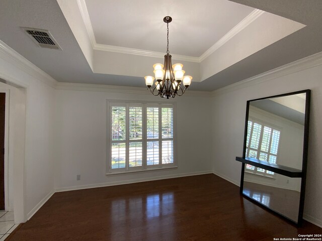 spare room featuring a raised ceiling, crown molding, a chandelier, and dark hardwood / wood-style floors