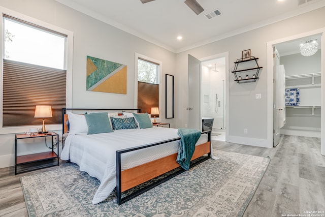 bedroom featuring connected bathroom, ceiling fan, crown molding, and light wood-type flooring