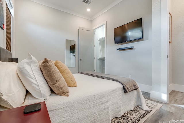 bedroom with ornamental molding and light wood-type flooring