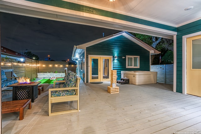 deck at night with french doors and an outdoor living space with a fire pit