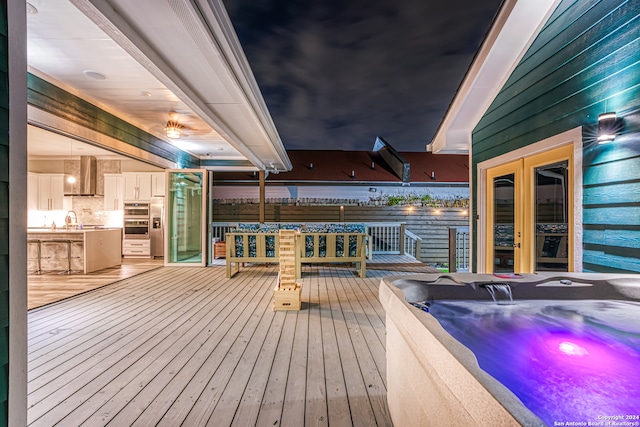 wooden deck with exterior kitchen, french doors, sink, and a hot tub