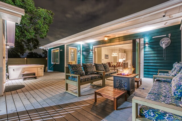 wooden deck featuring a hot tub and an outdoor living space with a fire pit