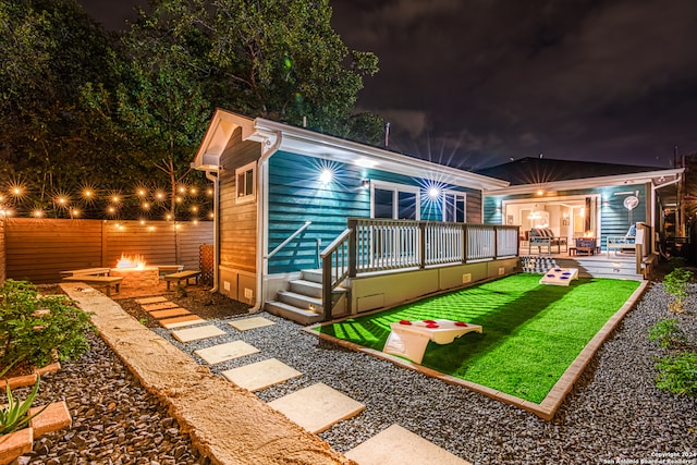 back house at twilight with a yard, a fire pit, and a wooden deck