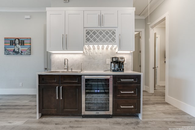 bar with light hardwood / wood-style floors, dark brown cabinets, beverage cooler, and sink