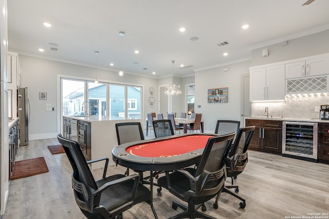 rec room featuring crown molding, light hardwood / wood-style flooring, beverage cooler, and wet bar