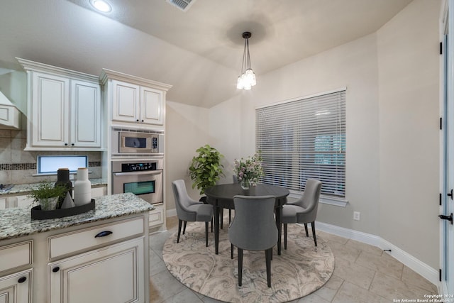 dining room featuring light tile patterned floors, vaulted ceiling, and an inviting chandelier