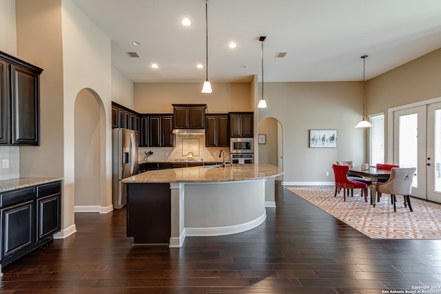 kitchen with appliances with stainless steel finishes, dark wood-type flooring, sink, pendant lighting, and a center island with sink