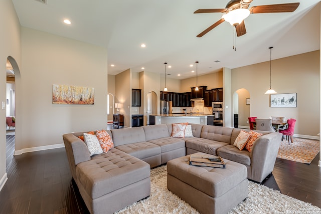 living room featuring ceiling fan, dark wood-type flooring, and a high ceiling