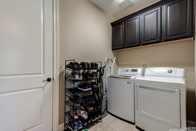 washroom with washing machine and clothes dryer, light tile patterned flooring, and cabinets