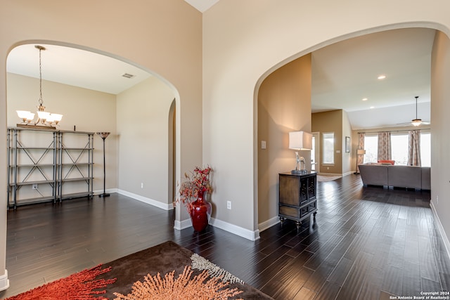 interior space featuring ceiling fan with notable chandelier and dark wood-type flooring