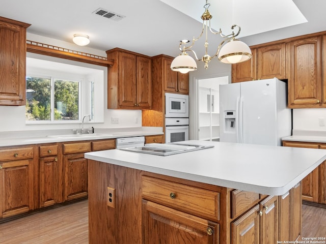 kitchen featuring sink, an inviting chandelier, light hardwood / wood-style floors, white appliances, and a kitchen island