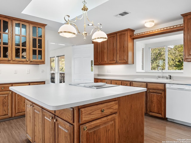 kitchen featuring dishwasher, sink, light wood-type flooring, a notable chandelier, and a kitchen island