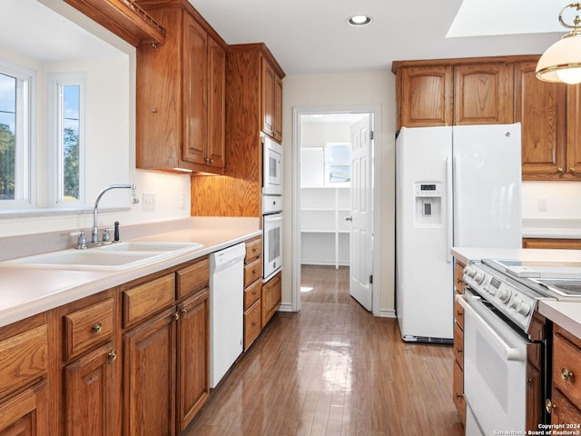 kitchen featuring pendant lighting, light hardwood / wood-style floors, white appliances, and sink