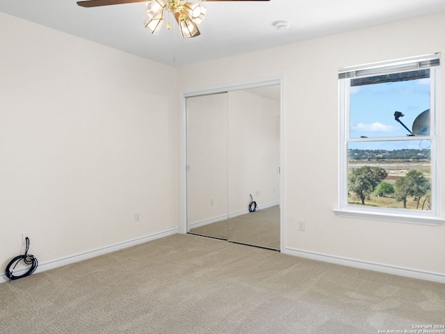 unfurnished bedroom with ceiling fan, light carpet, and a closet