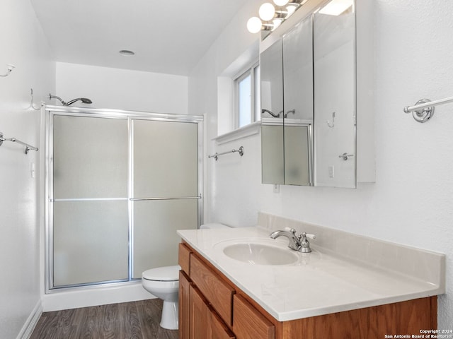 bathroom featuring hardwood / wood-style floors, vanity, toilet, and a shower with shower door