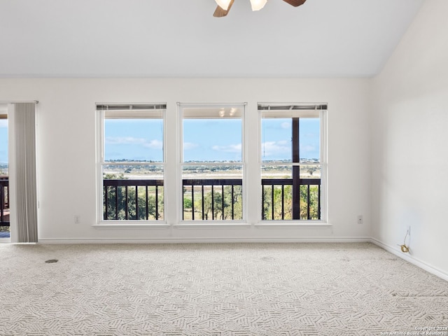 carpeted empty room featuring ceiling fan, plenty of natural light, and vaulted ceiling