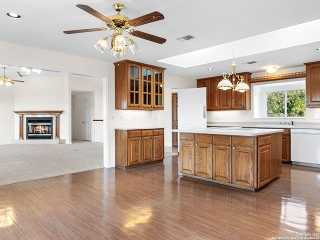 kitchen featuring a center island, white dishwasher, decorative light fixtures, dark carpet, and ceiling fan with notable chandelier