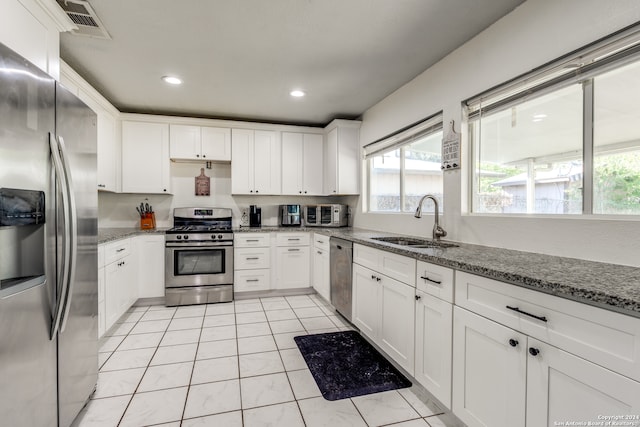 kitchen with appliances with stainless steel finishes, light stone counters, white cabinetry, and sink