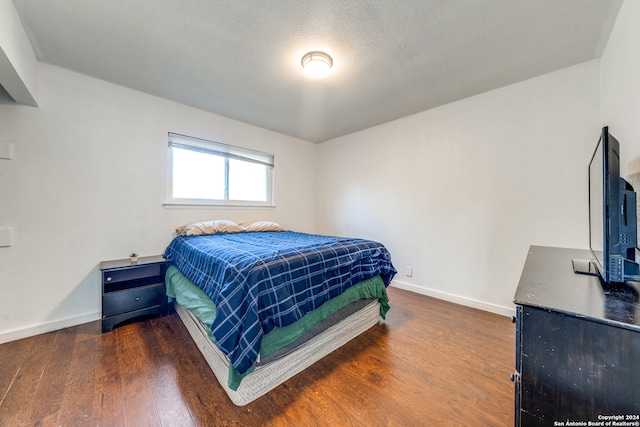 bedroom featuring dark hardwood / wood-style flooring and a textured ceiling