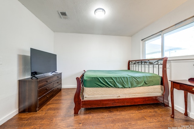 bedroom with a textured ceiling and dark wood-type flooring