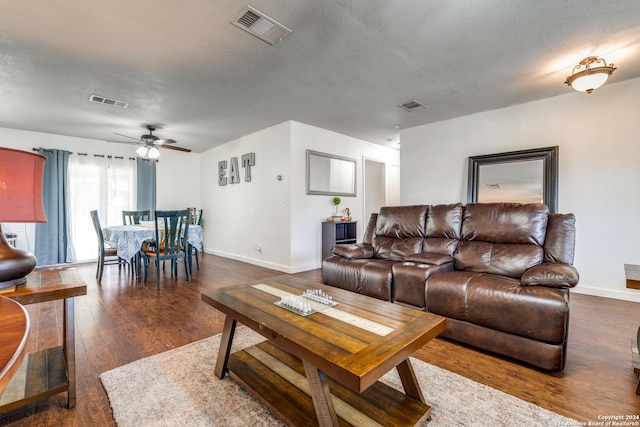 living room with a textured ceiling, dark hardwood / wood-style flooring, and ceiling fan