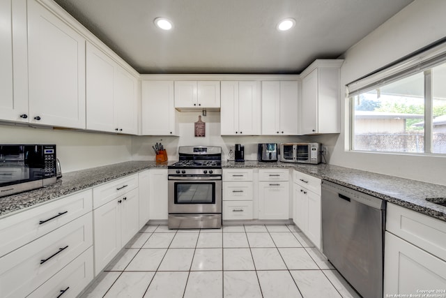 kitchen featuring light stone counters, white cabinets, light tile patterned flooring, and appliances with stainless steel finishes