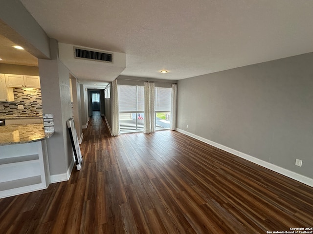 unfurnished living room with a textured ceiling and dark hardwood / wood-style floors