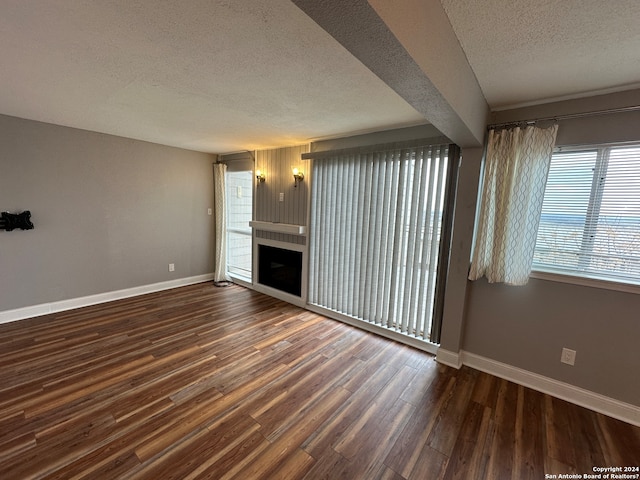 unfurnished living room with a textured ceiling and dark wood-type flooring