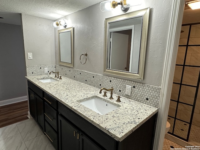 bathroom featuring vanity, a textured ceiling, toilet, and backsplash