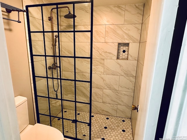 bathroom with a tile shower and toilet