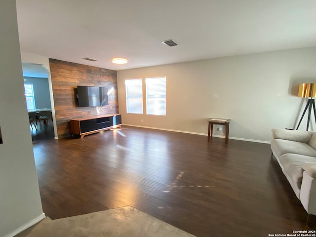 unfurnished living room featuring plenty of natural light and dark hardwood / wood-style flooring