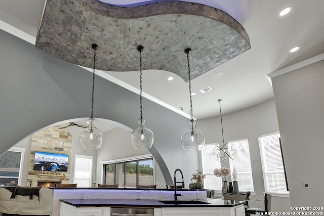 interior details featuring ceiling fan, sink, a stone fireplace, stainless steel dishwasher, and decorative light fixtures