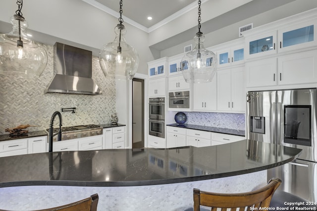 kitchen featuring pendant lighting, backsplash, wall chimney range hood, and stainless steel appliances