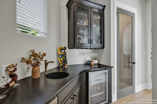 bar featuring dark brown cabinets, wine cooler, and sink