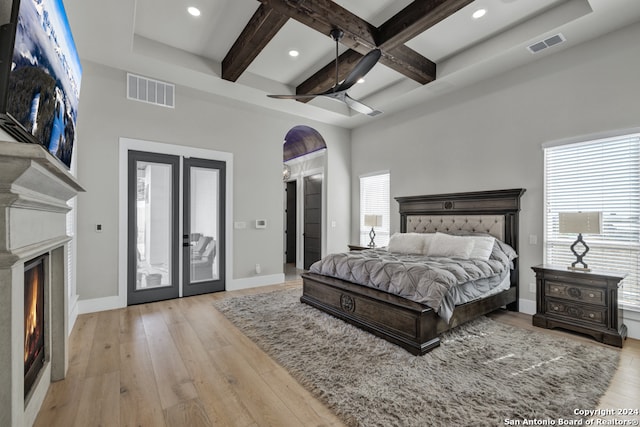 bedroom featuring ceiling fan, beam ceiling, multiple windows, and light hardwood / wood-style flooring