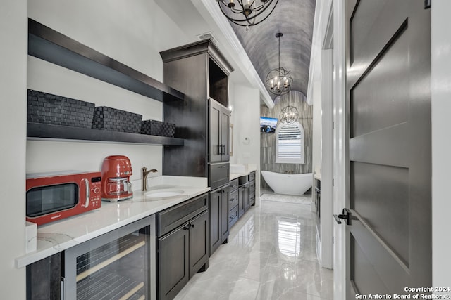 kitchen featuring pendant lighting, sink, wine cooler, light stone counters, and a chandelier