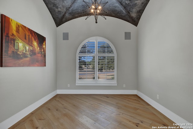 unfurnished room featuring a chandelier, vaulted ceiling, and light hardwood / wood-style flooring