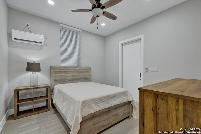 bedroom with ceiling fan, light wood-type flooring, and an AC wall unit