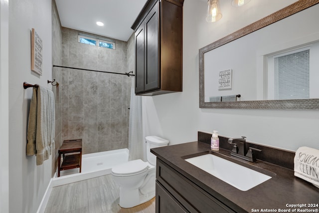 bathroom featuring a tile shower, vanity, and toilet