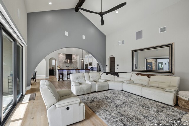 living room featuring beamed ceiling, ceiling fan, light hardwood / wood-style floors, and high vaulted ceiling