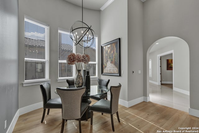 dining area featuring a chandelier, a towering ceiling, and light hardwood / wood-style flooring