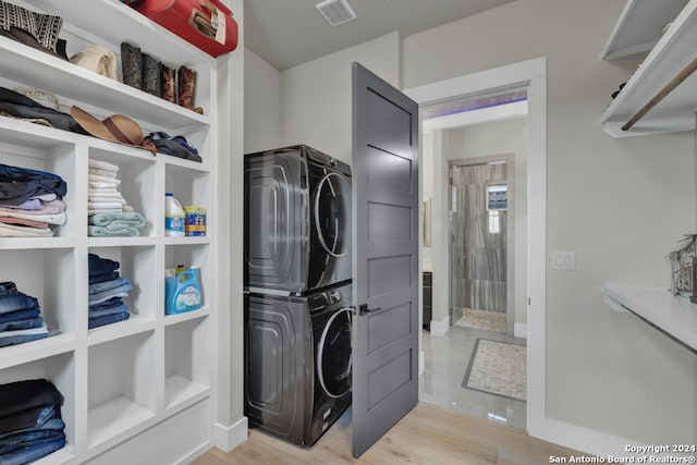 clothes washing area with stacked washer and dryer and light hardwood / wood-style floors