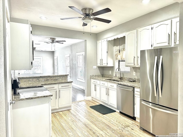 kitchen with light hardwood / wood-style floors, light stone counters, white cabinetry, and appliances with stainless steel finishes