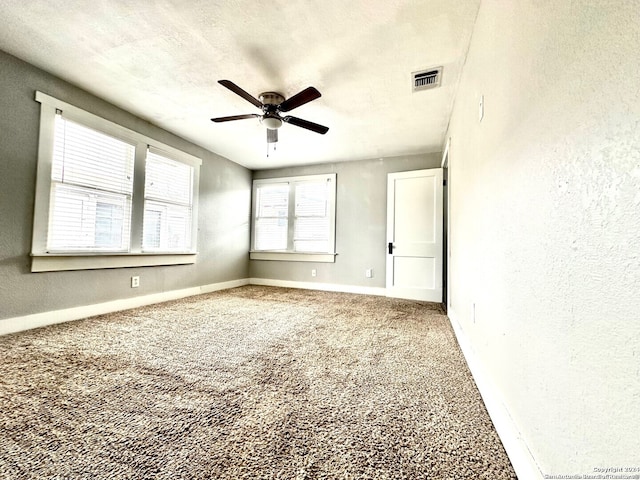 spare room with ceiling fan, carpet, and a textured ceiling