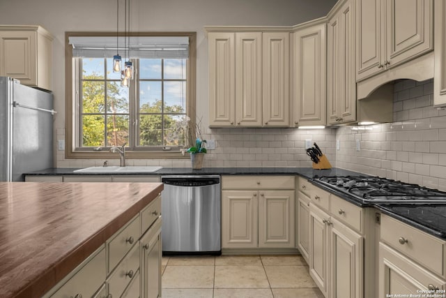 kitchen featuring wooden counters, appliances with stainless steel finishes, light tile patterned floors, and cream cabinets