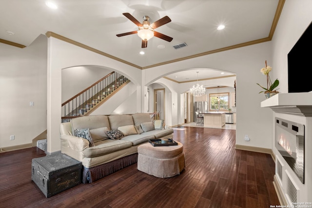 living room with crown molding, dark wood-type flooring, and ceiling fan with notable chandelier