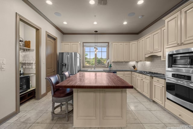 kitchen with stainless steel appliances, wooden counters, crown molding, pendant lighting, and cream cabinetry